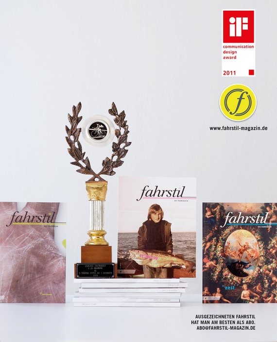 Ein Pokal für fahrstil, stehend auf einem Stapel Ausgaben mit stehenden Magazinen daneben.