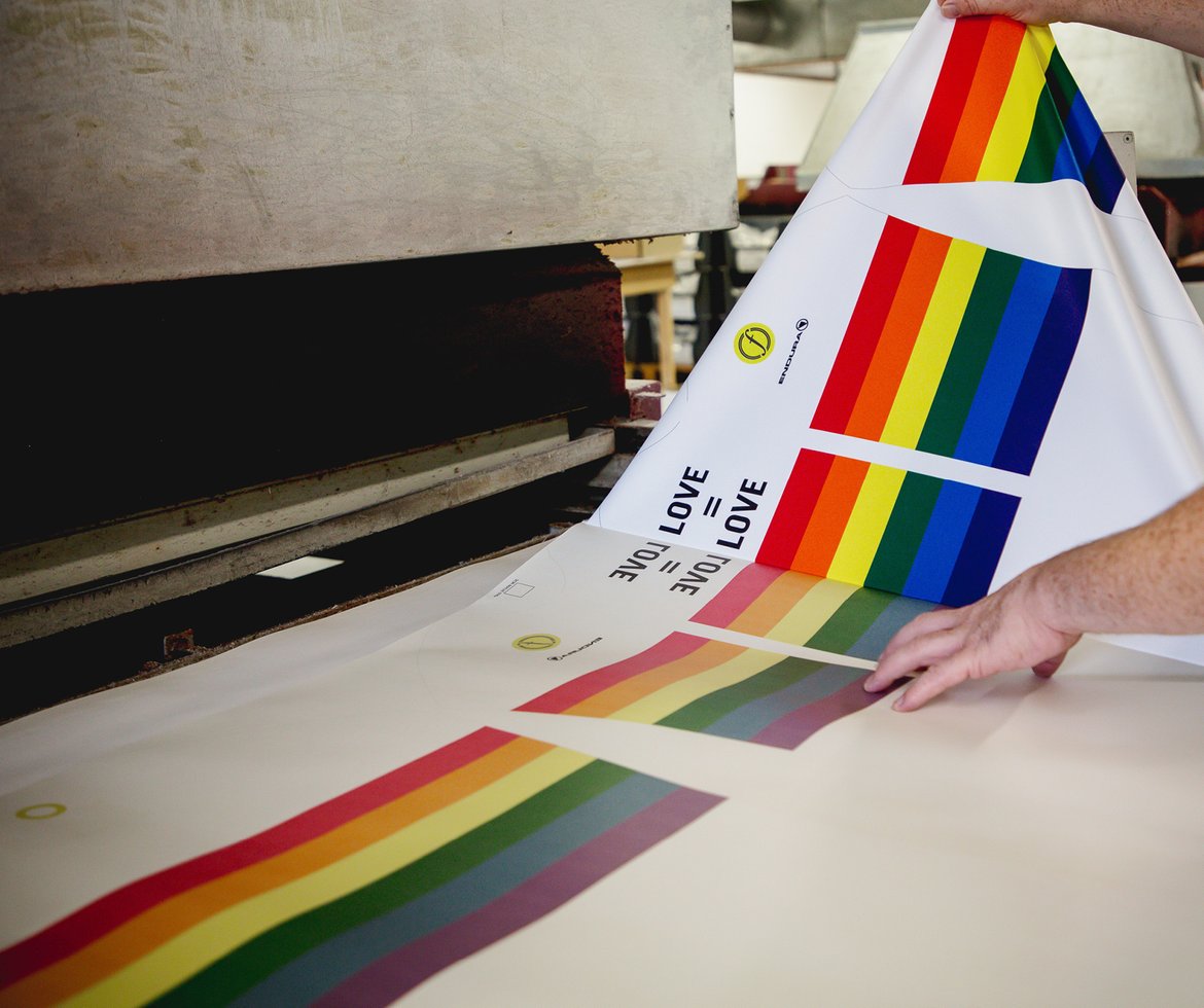 Stoff wird für die Trikots in Regenbogenfarben vor einer Druckpresse bedruckt.