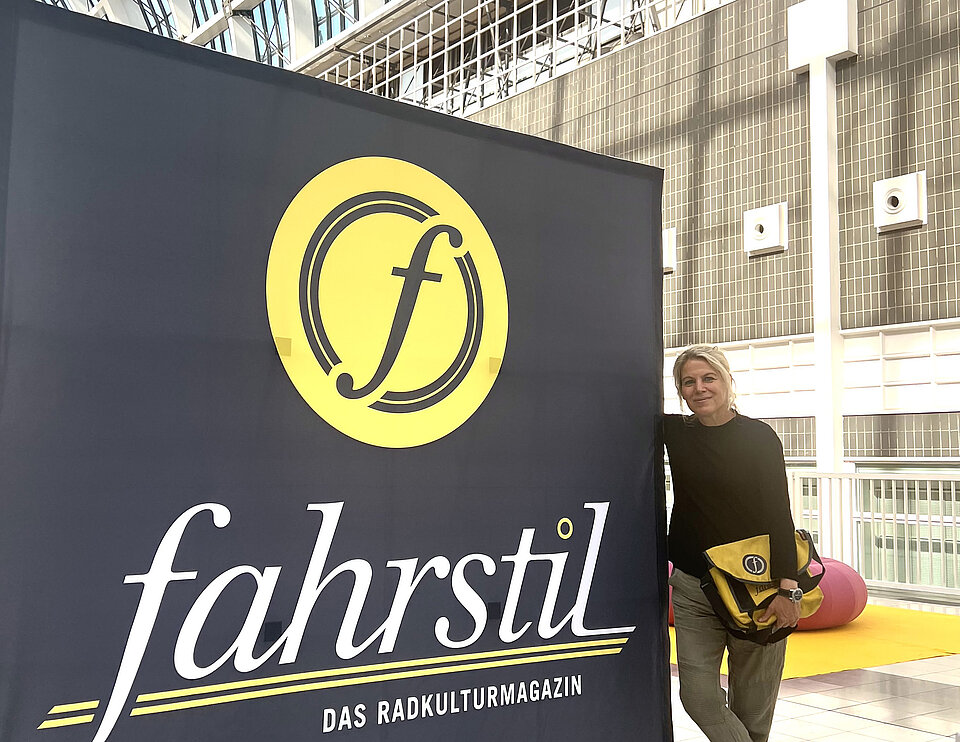 Janna Marten auf der Fahrradmesse Eurobike Frankfurt an einen fahrstil-Banner gelehnt. 