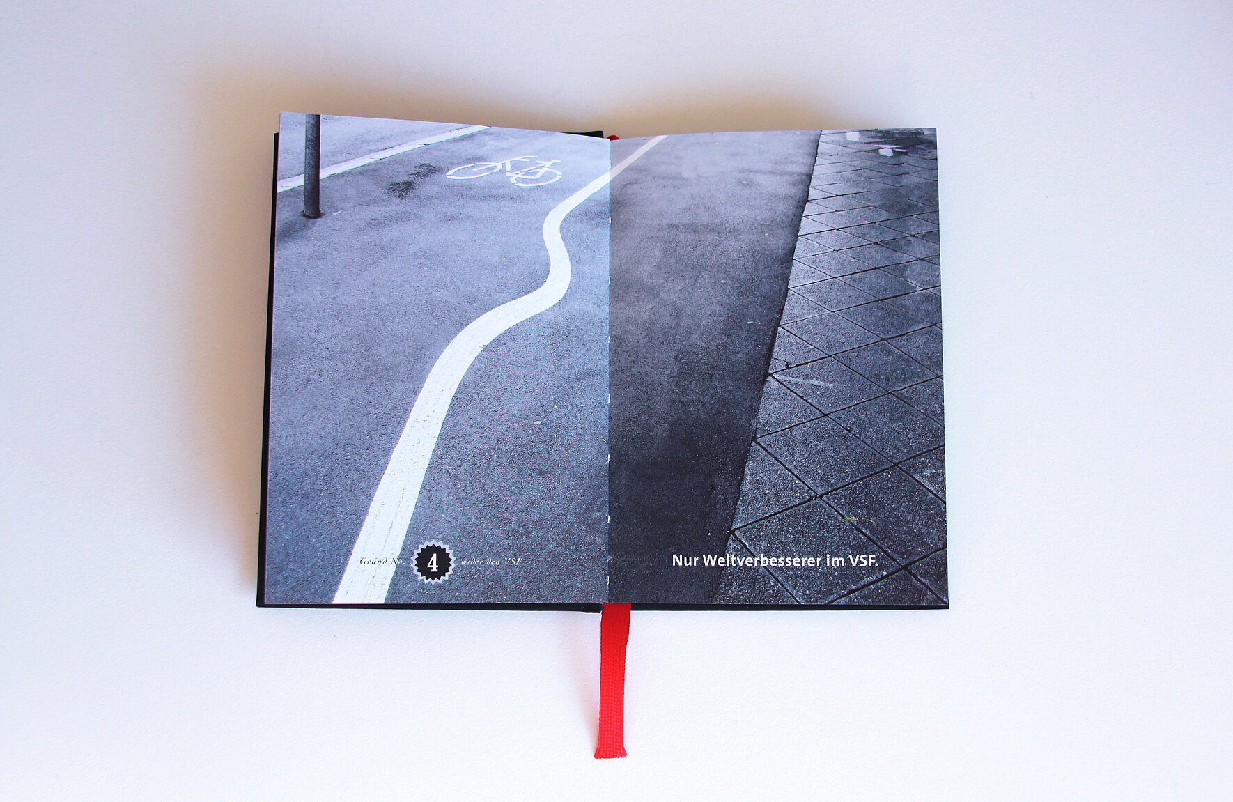 Ein aufgeschlagenes Buch mit einem Foto eines Radweges auf der Straße. 