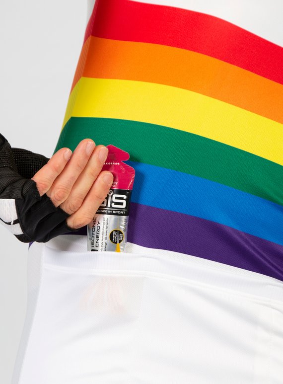 Eine Hand steckt in die Rückentasche des Trikots in Regenbogenfarben von fahrstil Energiegel.