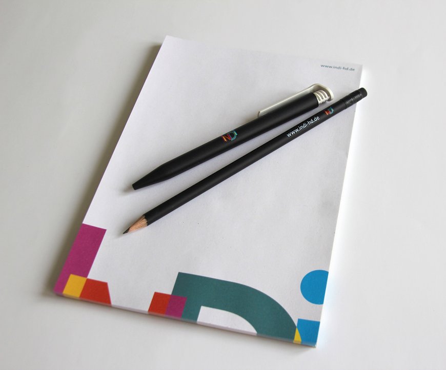 Ein Notizblock mit einem Bleistift und einem Kugelschreiber mit dem Logo der Individualhilfe Heidelberg.