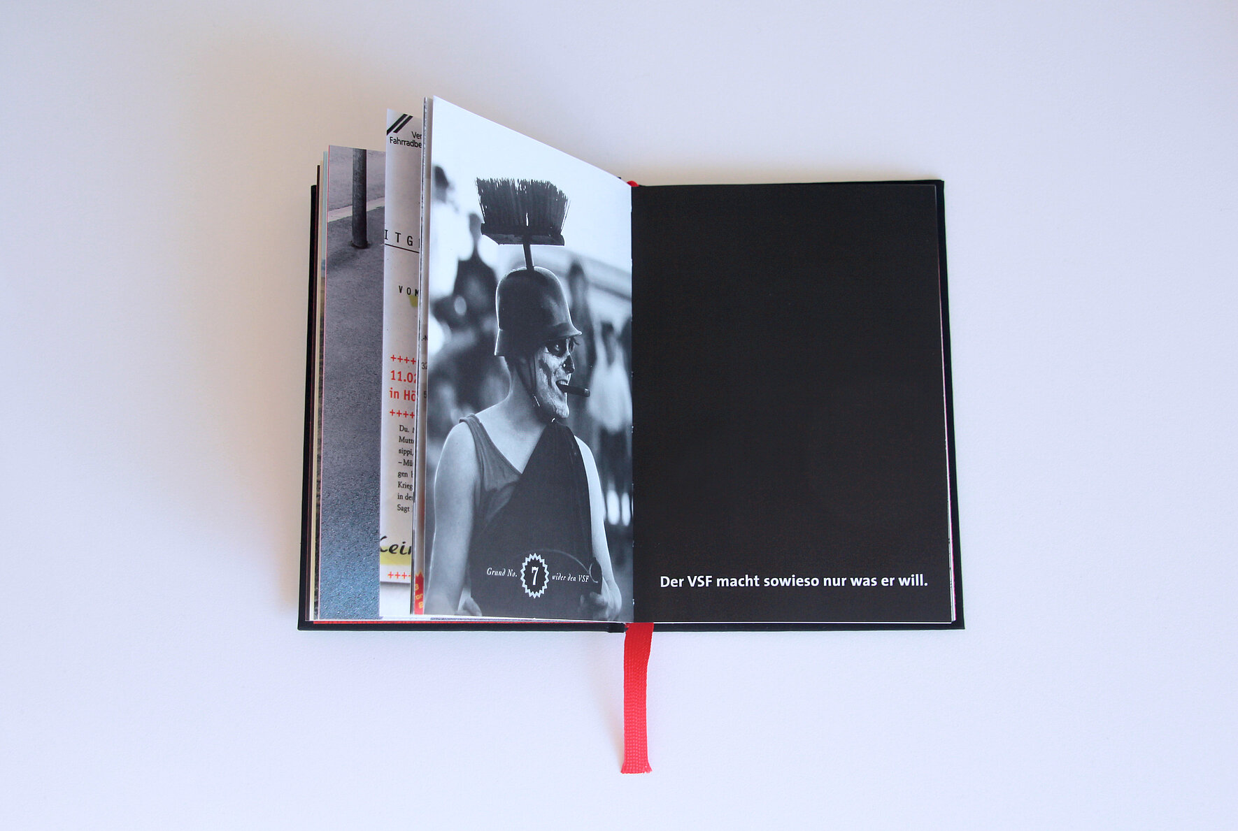Ein aufgeschlagenes Buch mit einer Fotografie auf der einen und einem Satz auf schwarzem Hintergrund auf der anderen Seite. 