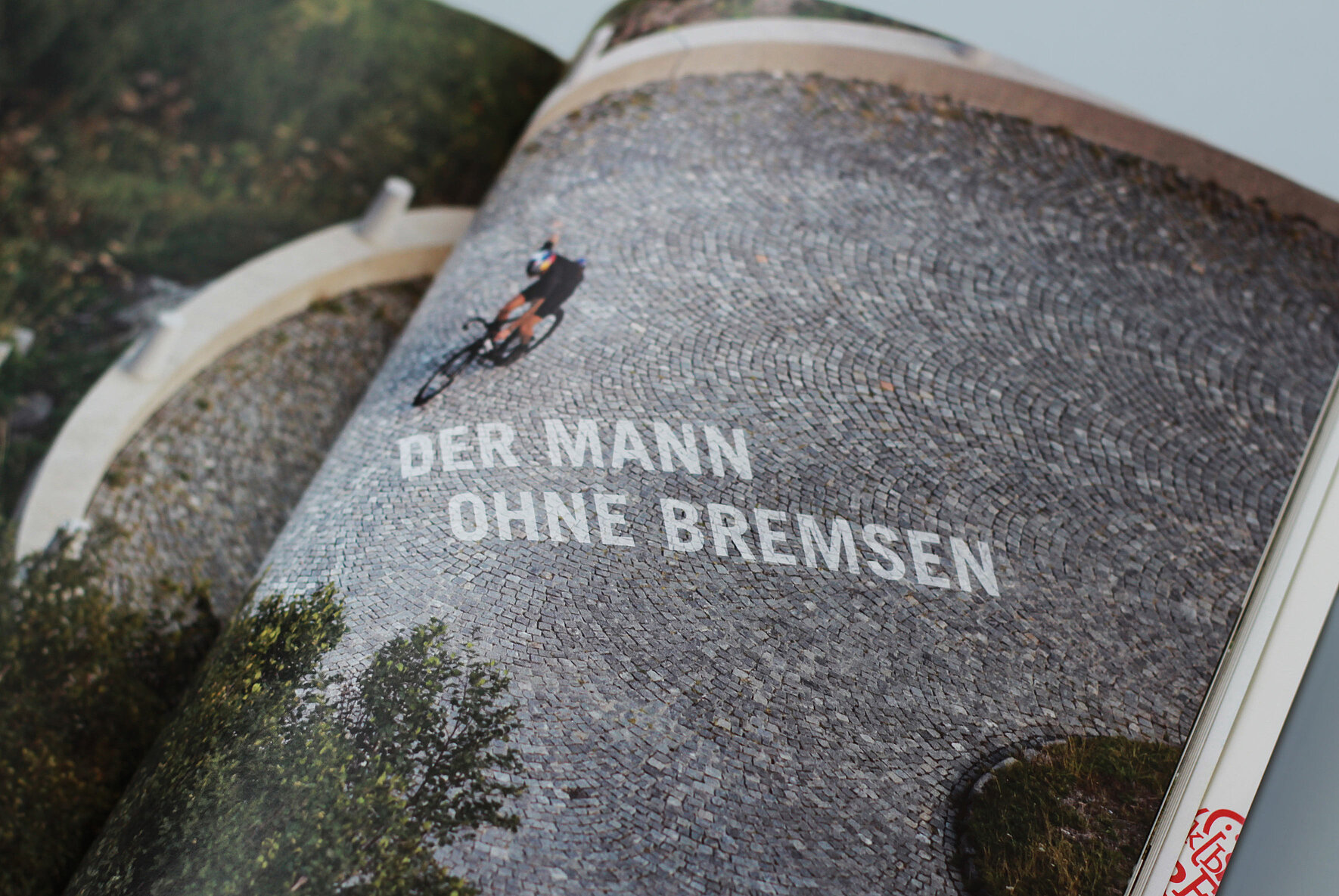 -	Eine aufgeschlagene Seite vom Magazin fahrstil kunst mit einem Radfahrer auf einem Hof und dem Schriftzug „Der Mann ohne Bremsen“.
